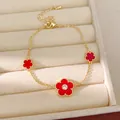 Elegantes vergoldetes Kettenarmband mit drei leuchtend roten Blumenanhängern und Zirkon - Armband / Gold / Rot