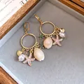 Elegantes pendientes de aro dorados con perlas, conchas y dijes de estrellas de mar rosa. - Estilo Clip de Aro / Marrón dorado