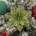 Primer plano de una flor de pascua verde con purpurina sobre un árbol de Navidad nevado. - Verde Militar