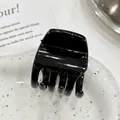Small glossy black triangle hair claw clip for high ponytail styling on a decorative plate - Triangle / Black Shiny Surface