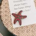 Detailed macro shot of a vintage starfish brooch with red and green rhinestones. - Fully Rhinestone Starfish In Red And Green Hues. Size: 4.5cm. Weight: 16 Grams.