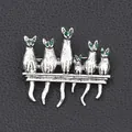 Vintage silver kitten brooch with green rhinestone eyes on black texture background - Retro Silver Row Cat Pin