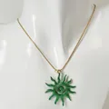 Gros plan d'un collier chaîne serpent dorée avec pendentif soleil spirale vert sur mannequin - Collier Soleil Spirale Ajouré (Vert)