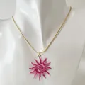 Zoom sur un collier avec pendentif soleil en spirale rose sur un buste de mannequin. - Collier Soleil Spirale Ajouré (Rose)