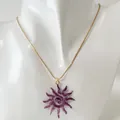 Détail d'un pendentif soleil évidé violet avec un motif en spirale sur chaîne dorée - Collier Soleil Spirale Ajouré (Violet)