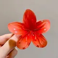Gros plan détaillé d'une pince à cheveux fleur de frangipanier rouge translucide - 8cm / Orange