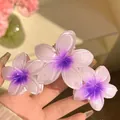 Vue détaillée des fleurs de frangipanier dégradées violettes sur une pince à cheveux. - Triple Fleur / Violet
