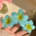 Vue détaillée de la pince à cheveux frangipanier bleue au centre jaune - Triple Fleur / Bleu