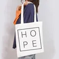Close-up of a white canvas tote bag with 'HOPE' print carried by a model. - HOPE Letters Style (8)