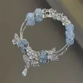 Blue crackle bead bracelet featuring silver butterfly charms on a shiny mirrored background. - Blue and White Cracked Style with Butterfly (S425)