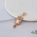 Detail van een schattige oranje kattenhanger met beweegbare staart en gouden sluiting - Bruin