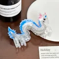 Close-up of a cute transparent acrylic dragon hair claw clip with blue accents on a table - Little Dragon