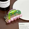 Close-up of a cute lizard-shaped acrylic hair claw clip on a wooden-textured base - Lizard