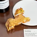Primo piano di una pinza per capelli in acrilico ambra a forma di cavallo su un piatto - Cavallo / 9.3cm