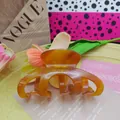 Detailed view of a tortoise shell acetate hair claw clip with Barrette la France engraving. - 10cm / Caramel color