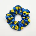 Close-up detail of a blue satin hair scrunchie featuring a vibrant yellow softball pattern - Blue Base Baseball