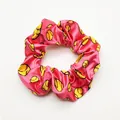 Close-up of pink satin scrunchie with yellow softball pattern print - Pink Base Baseball