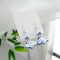 Elegant blue and white porcelain earrings with silver hooks displayed on a white jewelry card. - Blue And White Fan (1604-01)