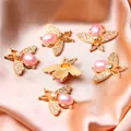 Close-up of golden alloy bee pendants with pink pearls for DIY jewelry making - Bee