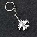 Polished silver metal fighter jet keychain on a textured black background - Airplane Style 3