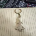 Detailed silver J-20 fighter jet metal keychain accessory on a lined notebook - J-20 Style