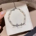Elegant pearl bracelet with zircon star charms in silver finish presented on a gift bag - Silver
