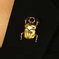 Detailed view of a golden beetle insect ring with polished metallic finish on black fabric. - Beetle Shape Brooch (12361) / Antique Gold