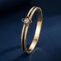 Elegant gold stainless steel bangle with Greek key pattern and clover crystal motif - Black Four Leaf Clover (40甲-B-5)
