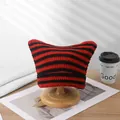Red and black striped handmade crochet cat-ear beanie displayed on a wooden stand. - One Size / Black Red