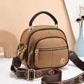 Close-up of brown pebbled leather handbag with decorative clover pattern wide strap - Khaki