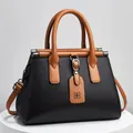 Vista dettagliata di una borsa nera con motivo litchi e manici marroni di classe - 28x14x20cm / Nero