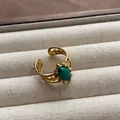 Detailed macro view of vintage gold-plated open ring with an oval green gemstone. - Hollow Carved Oval Green Gemstone Style (JZ0370) / Adjustable Open Ring (2cm) / Green