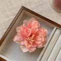 Gros plan d'une pince à cheveux pivoine rose dans un coffret à bijoux en velours - Rose Orangé