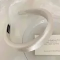 Gros plan sur un serre-tête élégant en satin crème rembourré pour un effet bombé - 15*16*3cm / Blanc Cassé