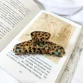 Detalle de una pinza de pelo grande de carey con brillo iridiscente sobre un libro - Patrón Floral Marrón-11cm