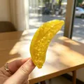 Detailed view of a yellow acetate banana-shaped hair claw clip in natural sunlight - Banana