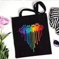 Black canvas tote bag featuring a vibrant rainbow dripping paw print heart design - Dripping Rainbow Paw Style (No. 4) / 35x40cm
