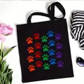 Black canvas tote bag featuring a vibrant rainbow paw print pattern for daily use - Multicolor Pet Paw Style (No. 12) / 35x40cm