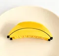 Vista detallada de una pinza para el pelo con forma de plátano sobre un plato - Forma de Plátano