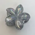 Gros plan d'une pince à cheveux fleur de frangipanier irisée au fini violet nacré - Gris
