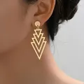 Eleganti orecchini pendenti geometrici a triangolo in oro indossati da modella - Stile a triangolo geometrico multistrato / Oro