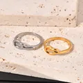 Macro view of polished gold and silver titanium steel knotted rings on textured stone. - Size 5 / Gold