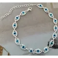 Silver evil eye bracelet featuring blue nazar beads on a textured grey fabric background - Silver Cyan Bracelet