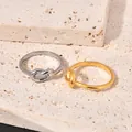 Detailed top view of minimalist silver and gold knot rings on textured stone blocks - Size 5 / Steel