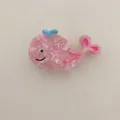 Close-up detail of a cute pink whale-shaped acetate hair claw clip for women - Whale