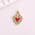 Close-up of a vintage gold heart pendant with red enamel center and filigree detail. - Red