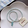 Detail view of summer island beaded necklace with a blue fish pendant on a white plate. - No.7 Little Fish