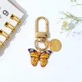 Golden keychain featuring a vibrant yellow and orange oil-dripped butterfly charm - Orange Yellow Gradient Style (F)