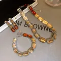 Close-up of champagne and amber rectangular stone jewelry set on grey background - Stud Earrings Bracelet Necklace - White