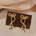 Close-up of elegant gold-plated bow earrings with irregular vintage hammered texture - Bowknot Hammered Style (E5179) / Gold